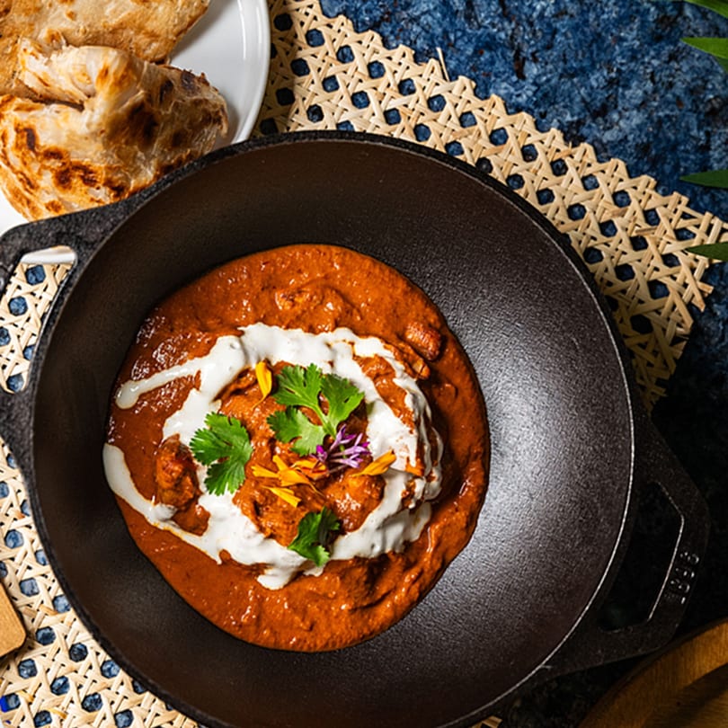 ZEN Kitchen & Bar's Asian-fusion butter chicken in a cast iron pan with naan bread.